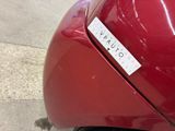 a sticker on the back of a red car that is parked on the side of the road
