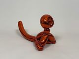 a shiny red balloon dog sitting on a white surface