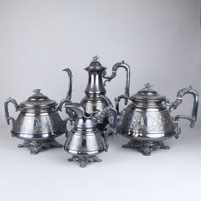 four pieces of silver tea and coffee set on a white surface