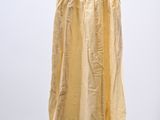 yellow dress hanging on a black hanger against a white wall