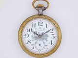 a gold pocket watch hanging on a white wall