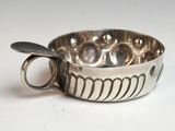 une tasse en argent posée sur une table, avec une cuillère à l'intérieur