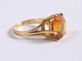 a close up of a yellow gold ring with an orange topaz stone