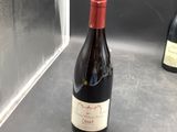 a bottle of wine sitting on a counter next to two bottles of wine