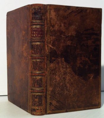 un vieux livre à la couverture marron posé sur une table blanche