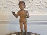 une petite statue représentant un garçon, posée sur une table en marbre