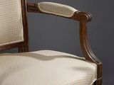 a close up of a wooden chair with a beige upholstered seat