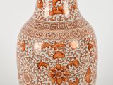 un vase orange et blanc posé sur une table blanche