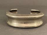 bracelet manchette plaqué argent, au motif incurvé sur une surface grise