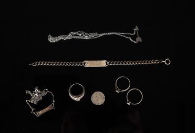 des bijoux en argent sur fond noir, comprenant une chaîne, un bracelet, une bague et d'autres articles