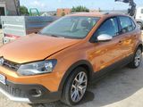 an orange vw cross parked in a parking lot next to a trailer