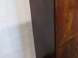 a tall wooden cabinet with a drawer underneath it