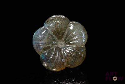 une image représentant une fleur en verre posée sur une surface noire