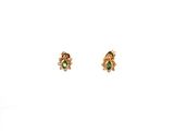 une paire de boucles d'oreilles en or ornées de pierres vertes sur fond blanc