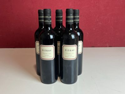 trois bouteilles de vin posées sur une table devant un mur rouge