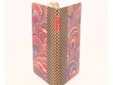 an old book with a red and blue cover sitting on top of a white surface