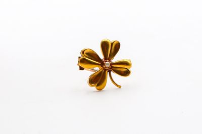 un gros plan d'une bague en forme de trèfle à quatre feuilles posée sur une surface blanche