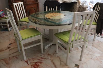a table and chairs in a room with a painting on the table