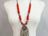 a mannequin torso with a red beaded necklace and silver bells