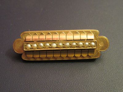 a gold pin with pearls on it sitting on a table