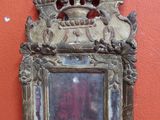 un petit miroir posé sur une table près d'un mur