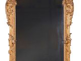 an ornately carved mirror with a black background and a gold frame
