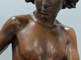 a bronze statue of a boy holding a tennis racquet