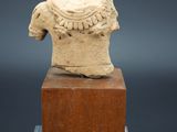 une statue ancienne représentant une tête posée sur un bloc de bois