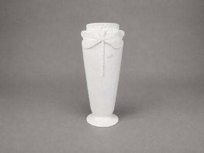 un vase blanc orné d'un nœud, sur fond gris