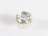 un gros plan d'une bague sertie d'une topaze bleue sur une surface blanche