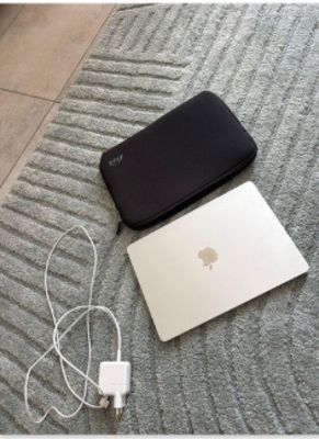 un ordinateur portable et un chargeur posés par terre à côté d'un téléphone portable