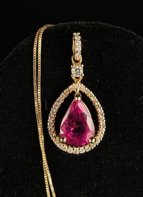 a pink stone and diamond pendant on a gold chain