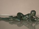 statue of a woman laying on her stomach on a glass table