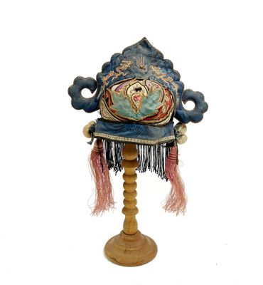 un chapeau bleu posé sur un support en bois, sur fond blanc