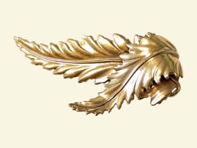 a gold leaf brooch on a white background