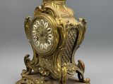 une horloge en or posée sur un socle, surmontée d'un oiseau