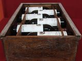 des bouteilles de vin sont disposées dans une caisse en bois posée sur une surface rouge