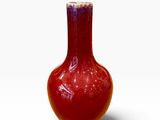 un vase rouge posé sur une surface blanche