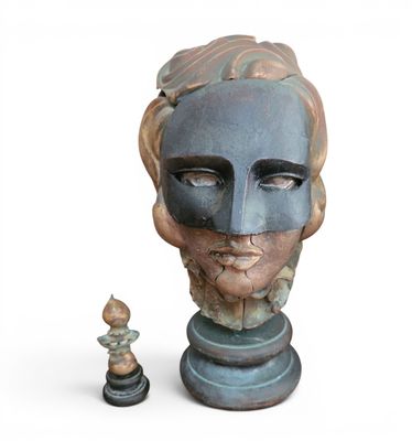 a statue of a man with a mask next to a chess piece