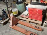 une palette posée à même le sol, à côté d'une pile de cartons