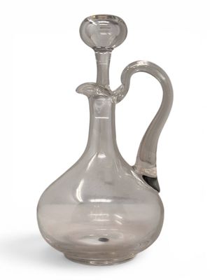 a clear glass bottle with a handle on a white surface