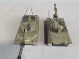 two toy tanks sitting next to each other on a white surface