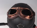 leather motorcycle helmet with goggles attached to it on a white surface