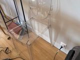 a clear chair sitting on a wooden floor next to a table