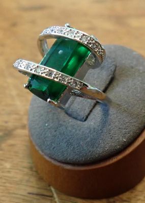 an image of a ring with a green stone and diamonds on it