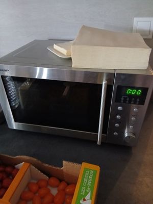 un four à micro-ondes posé sur un plan de travail, à côté d'une boîte de tomates
