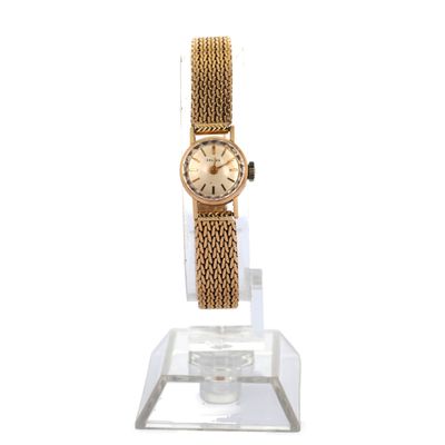 une photo d'une montre-bracelet en or posée sur un socle transparent