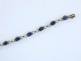 a close up of a bracelet with blue stones on a white surface