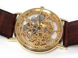 a close up of a gold watch with a brown strap