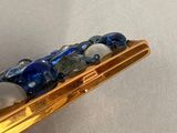 a gold plated object with blue and white stones on it